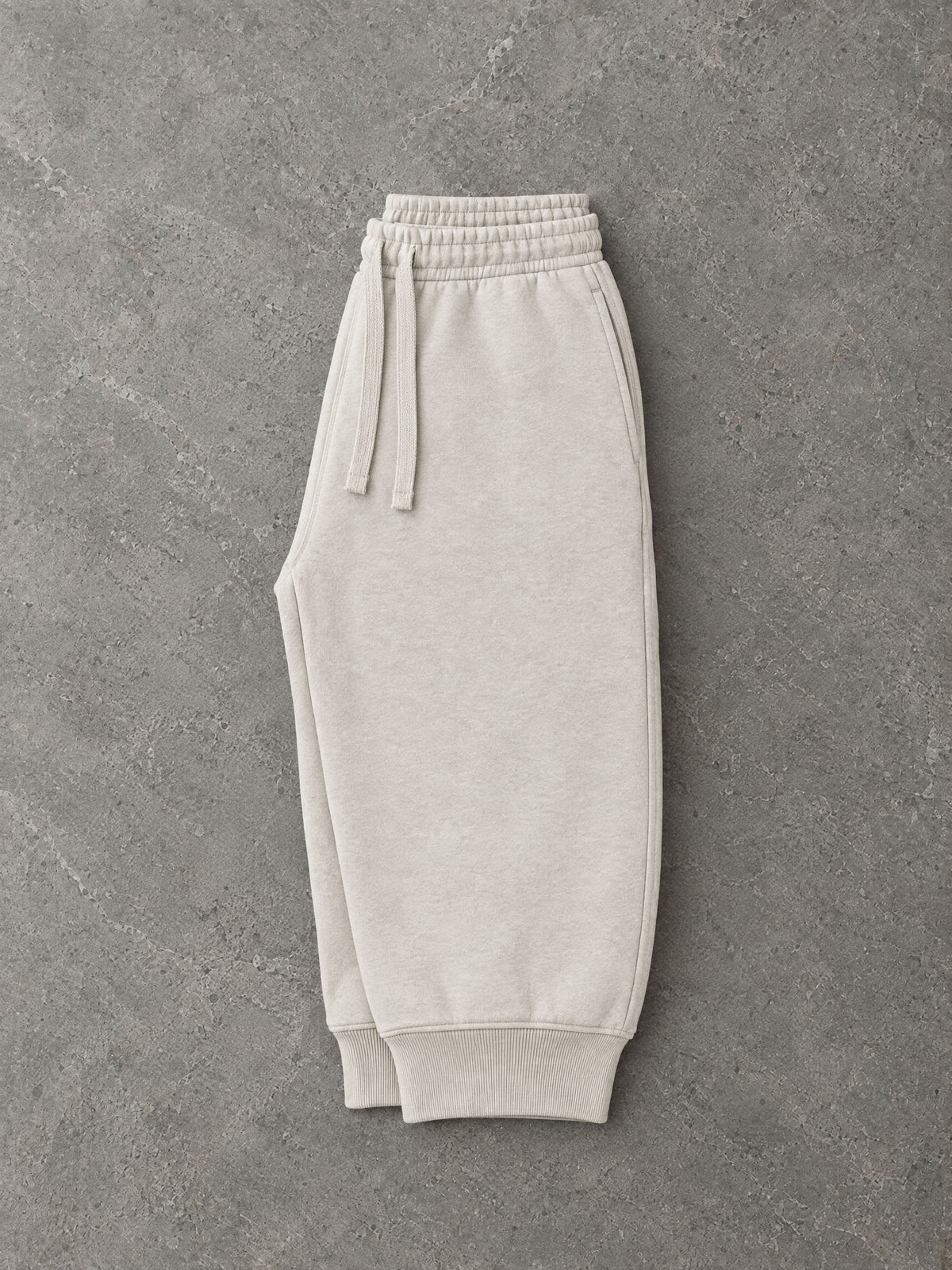 Lot 001 The Loopback Sweatpant in Bone, folded flat on stone